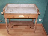 a wooden table with a marble top in the corner of a room
