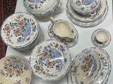many plates and bowls on the table with blue and orange flowers