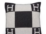 un coussin à carreaux noirs et blancs sur lequel figure la lettre « h »