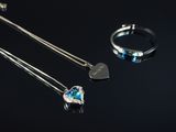 deux colliers et une bague avec un cœur sur fond noir