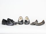 trois paires de chaussures noires sont alignées sur une surface blanche