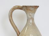 a small vase with a handle on a white surface