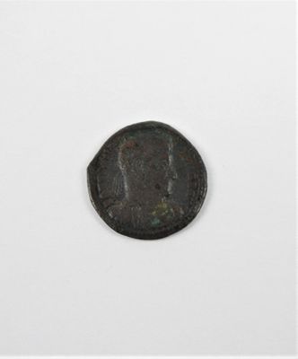 une vieille pièce de monnaie sur laquelle figure un visage, posée sur une surface blanche