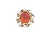 un gros plan d'une bague ornée de perles et d'une pierre orange
