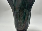 un vase noir posé sur une table blanche