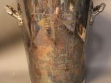 a silver vase with a picture on it on a table