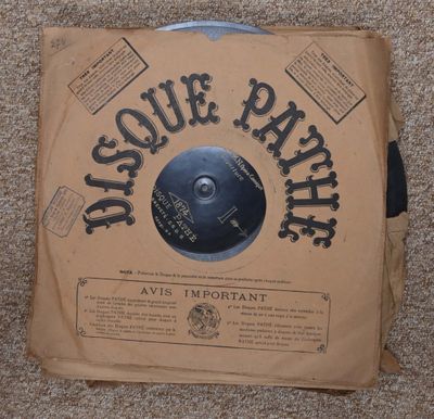 une photo d'un disque vinylique dans une boîte en carton posée sur un sol recouvert de moquette