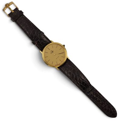 a gold plated wrist watch with a black alligator skin strap