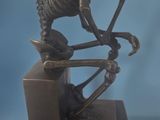 statue of a skeleton sitting on a box with a ball in his hand