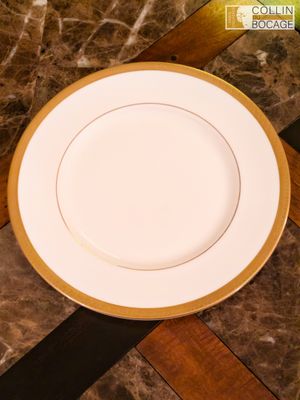 une assiette blanche à bord doré posée sur une table en marbre