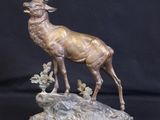 bronze sculpture of a stag on a rock with a black background