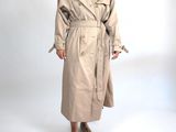 une femme en trench-coat posant devant l'appareil photo