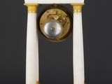 a white and gold clock on a stand on a black background
