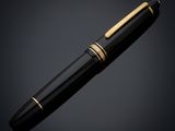a black and gold pen with a gold tip on a dark background