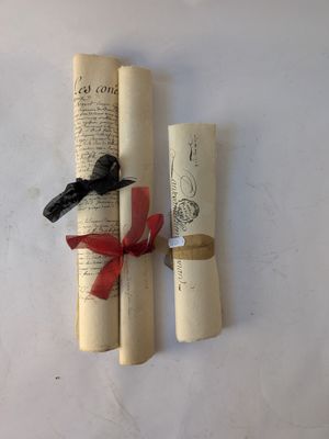 two rolled up scrolls with a red ribbon tied to them