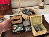 un panier rempli de bijoux posé sur une table, à côté de la main d'une personne