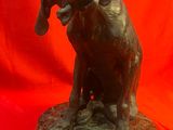 statue en bronze représentant un chien la gueule ouverte sur fond rouge