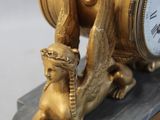 a gold clock with a cat sitting on top of it