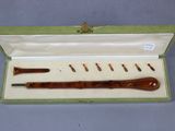 an image of a wooden pipe in a green box with a white lid