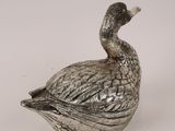 a silver duck that is sitting on top of a bowl