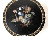 a black plate with a painting of flowers on it