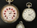 trois montres de poche différentes posées sur une surface noire