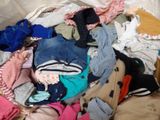 a pile of clothes that is sitting on a bed