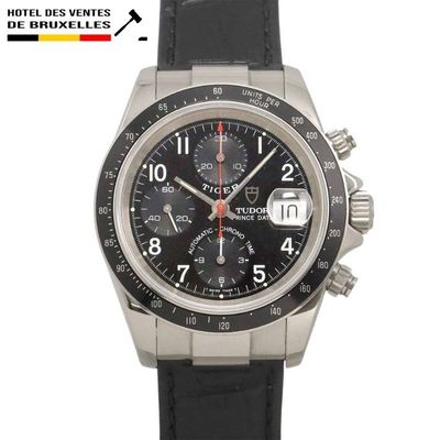 La montre est noire et argentée, avec une trotteuse rouge.