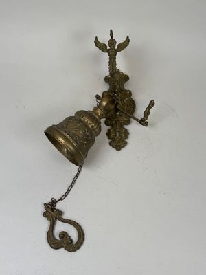 a brass bell hanging from a hook on the wall
