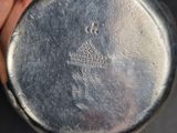 someone is holding a silver watch in their hand on a black surface