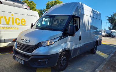 a silver van parked in a parking lot next to a bus