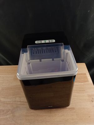 un petit récipient en plastique muni d'un couvercle, posé sur une table en bois
