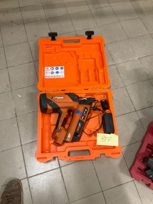 une boîte à outils contenant un marteau et une cloueuse, posée par terre