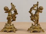 pair of antique brass figurines of cherensils on a pedestal