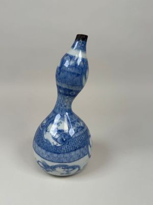 un vase bleu et blanc en forme de calebasse posé sur un fond blanc