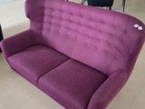 a purple couch sitting in a living room next to a black chair