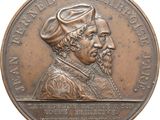 an image of a bronze medal with a portrait of a man and a woman