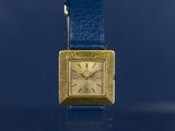 a gold watch with a blue strap around it