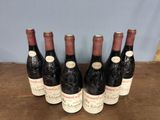 six bottles of wine are lined up on a wooden table