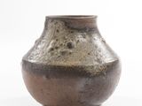 a brown vase that is sitting on a white surface