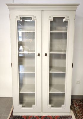 une photo d'une bibliothèque blanche avec des portes vitrées et un tapis au sol