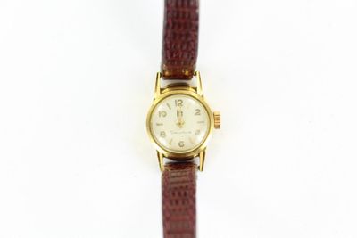 une image d'une montre en or avec un bracelet en cuir marron