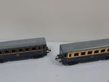 two toy trains are sitting on a white surface