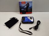 a small blue camera sitting on a table next to a black bag