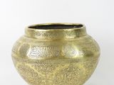 a gold vase that is sitting on a white surface