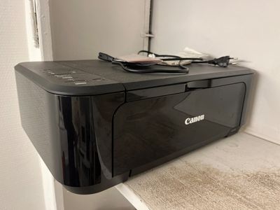 une imprimante Canon posée sur une étagère dans une pièce