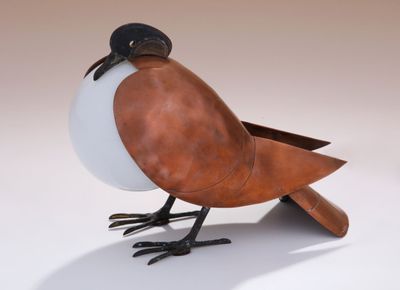 a bird that is sitting on the ground with a ball in its beak