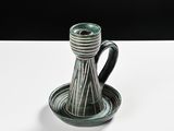 a black and green vase with a saucer on a white table