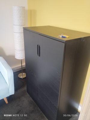 une armoire noire dans une pièce, avec une chaise bleue à côté