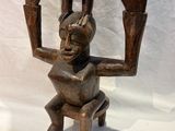 wooden sculpture of a woman holding a cat on her head
